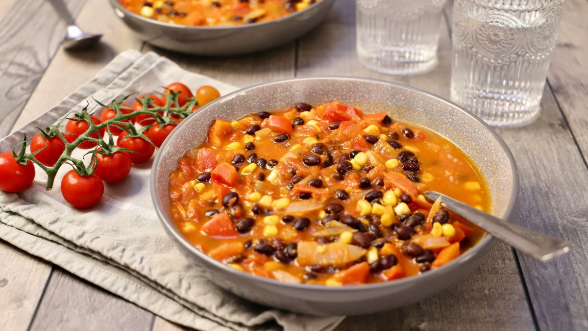 Zuppa fredda estiva con legumi, mais, pomodorini e ortaggi freschi, servita in ciotola rustica. Ricetta antispreco dalla cucina ciociara.